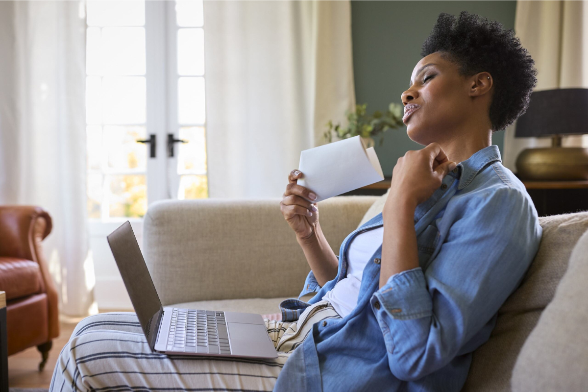 African-American woman experiencing a hot flash while reviewing company menopause benefits.| Corporate Synergies